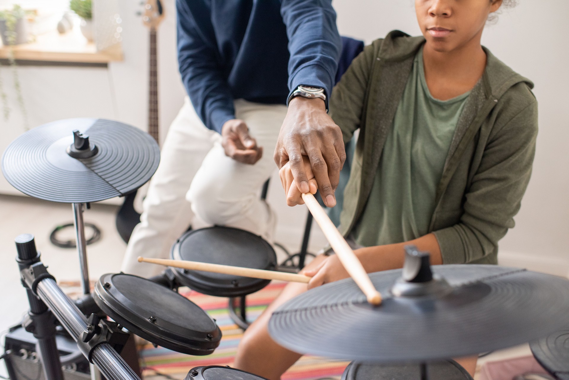 African male teacher explaining schoolgirl how to play drumkit